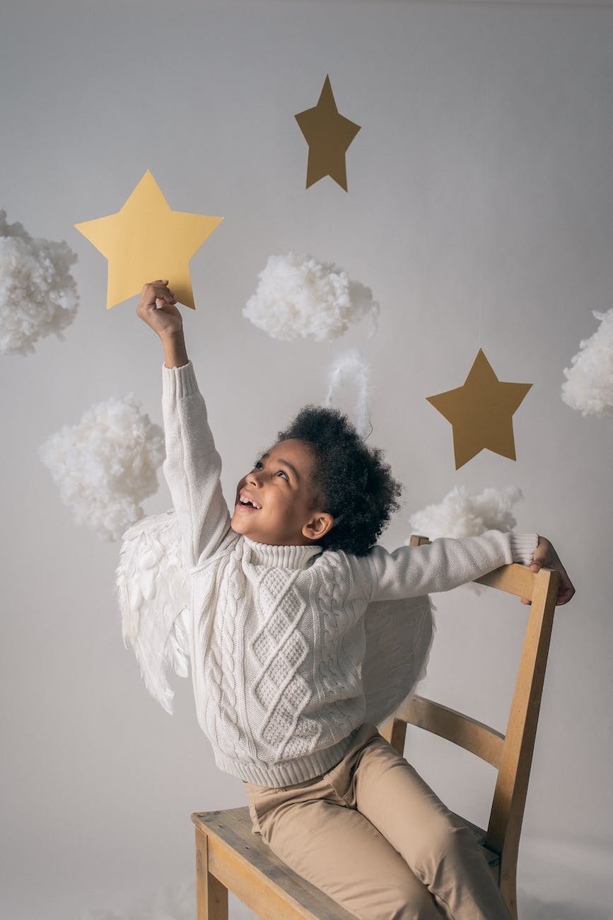 happy black boy reaching out to decorative star from chair