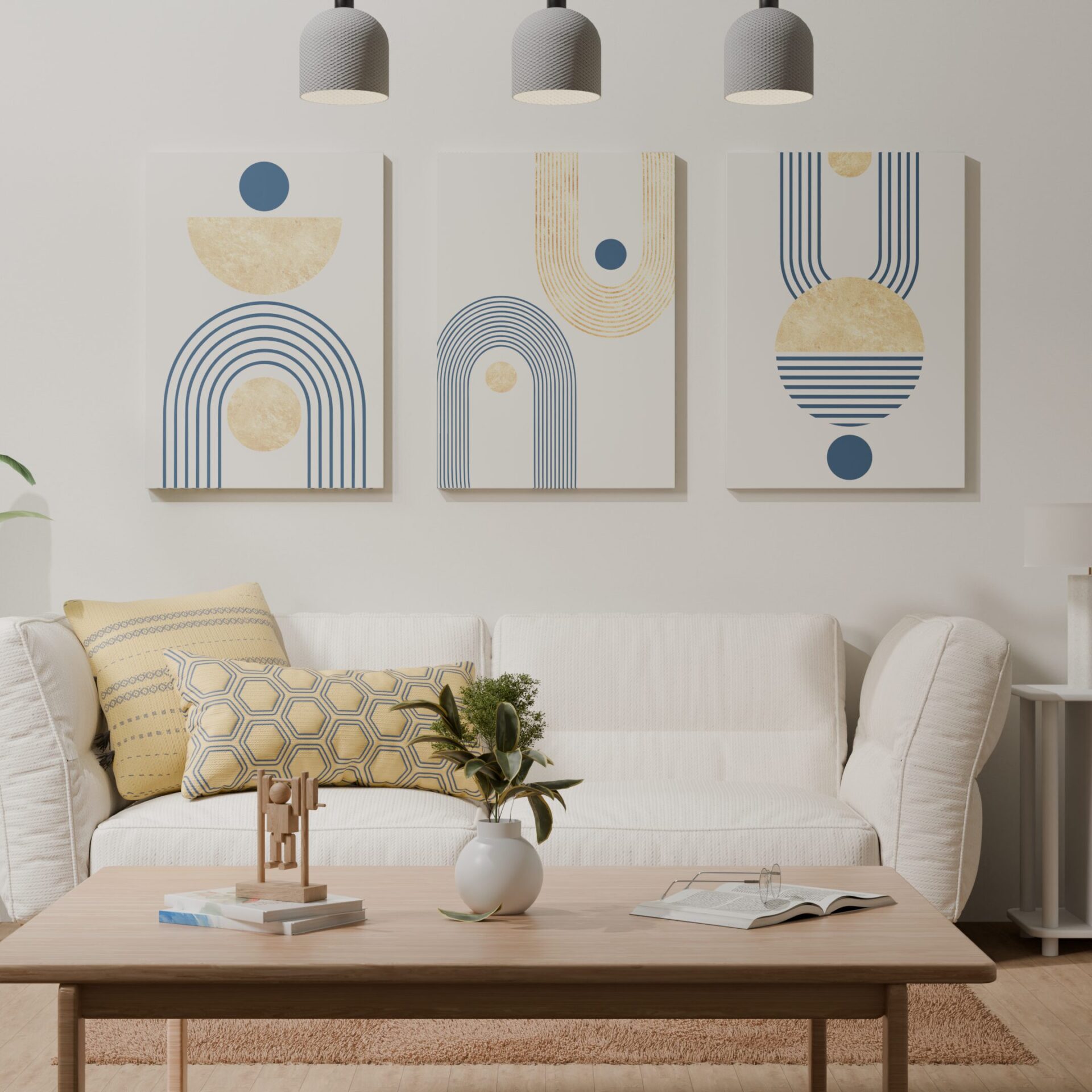 Living room with a white sofa adorned with yellow patterned pillows. Above the sofa are three abstract art canvases with geometric designs in gold and navy blue, featuring circles, semi-circles, and arches. A small potted plant and a wooden decorative piece are placed on a light wooden coffee table in front of the sofa.