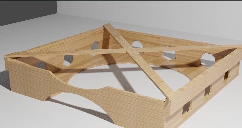 A wooden frame structure with cross beams and circular cutouts, placed on a light-colored surface. The structure resembles the assembly of a paper plate dispenser.