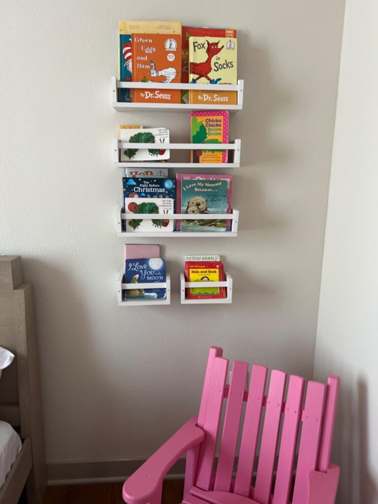 baby book shelf setup with four stacked white shelves holding a collection of children's books, creating a neat and accessible reading space.