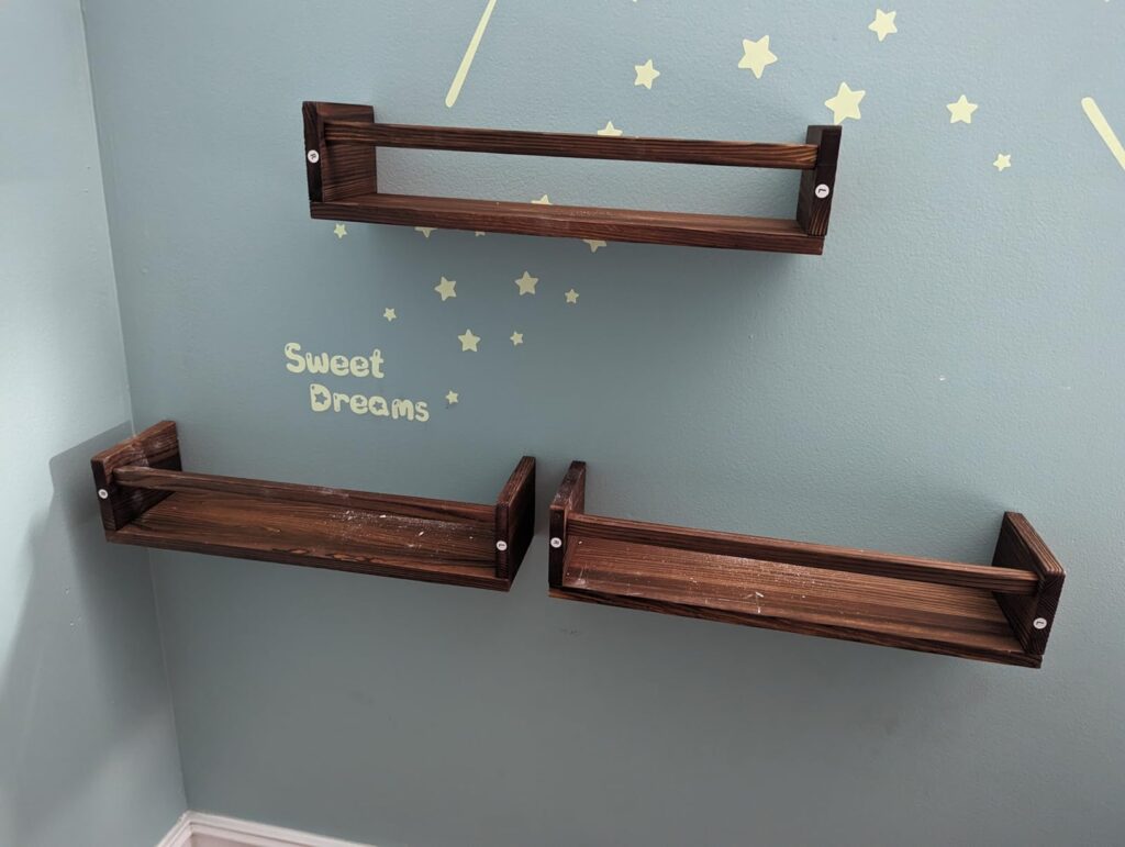 Brown colored Nursery shelves for wall mounted on a grey wall with some stars and 'Sweet Dreams' written next to it.