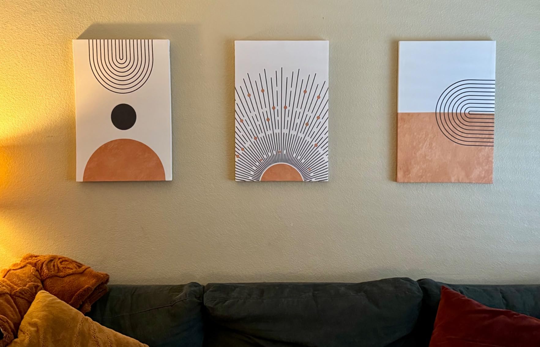 Three boho artwork for wall displayed above a sofa, showcasing geometric designs in earthy tones that match the living room decor. A perfect arrangement of boho canvas wall art to create a warm and inviting atmosphere.