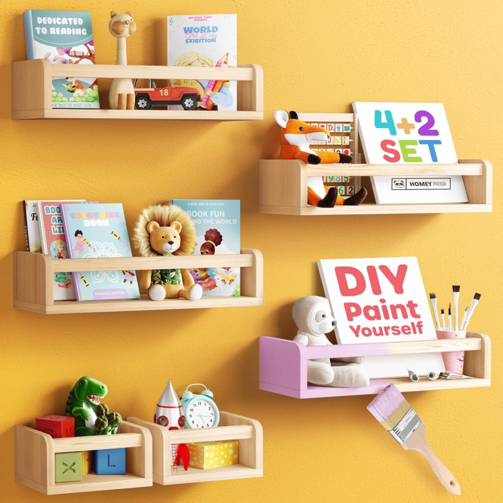 Floating nursery shelves mounted on a yellow wall, holding children's books, plush toys, educational blocks, and art supplies. The shelves are in natural wood, with one shelf painted pink, creating a playful and organized display for a child's room.