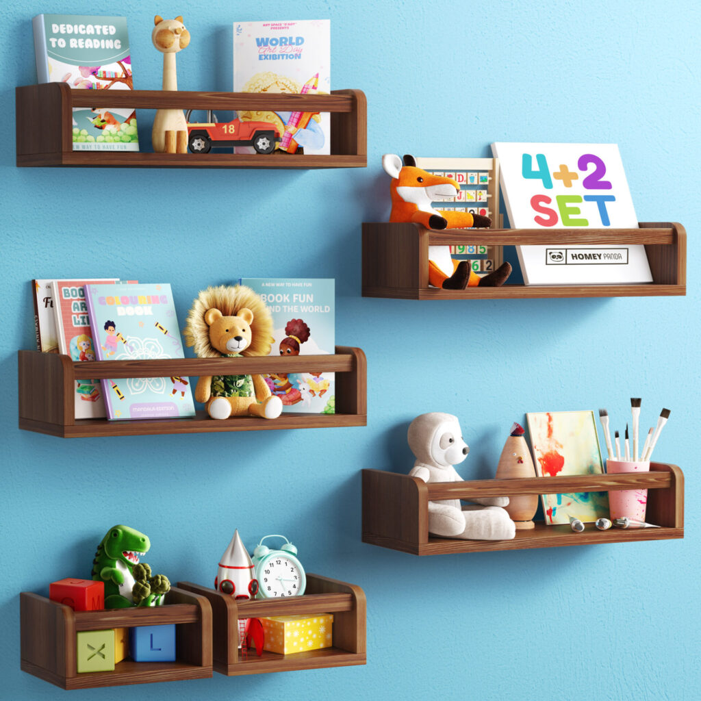 Floating nursery book shelves mounted on a blue wall, holding children's books, plush toys, educational blocks, and art supplies. The shelves are in natural wood, with one shelf painted pink, creating a playful and organized display for a child's room.