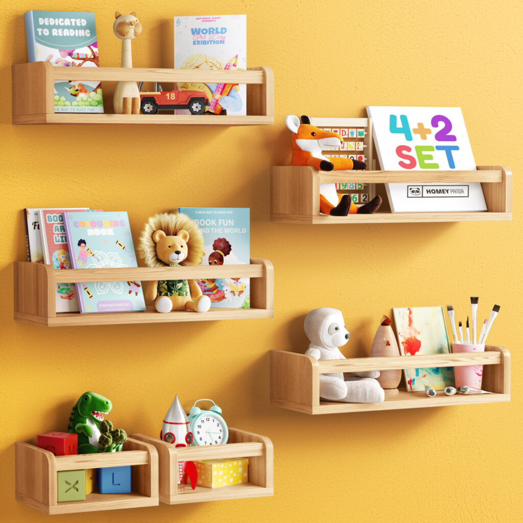 Floating nursery book shelves mounted on a white wall, holding children's books, plush toys, educational blocks, and art supplies. The shelves are in natural wood, with one shelf painted pink, creating a playful and organized display for a child's room.