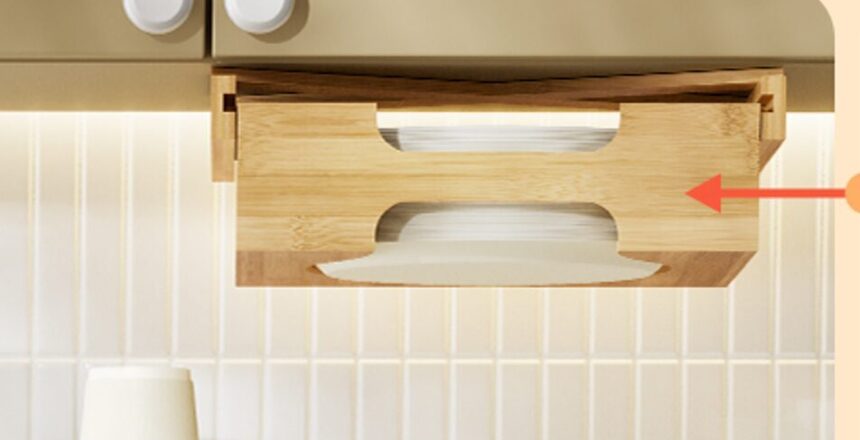 Bamboo paper plate holder mounted under a cabinet with stacked plates visible, above cups and a marker on the countertop.
