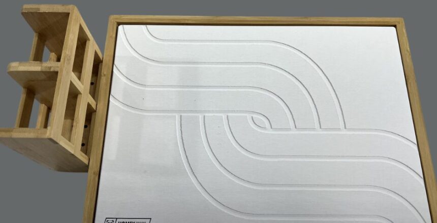 Top view of a white stone drying mat with an abstract curved line design, placed within a wooden frame. A wooden holder is attached to the side for organizing utensils or accessories. The mat is branded with 'Homey Panda'.