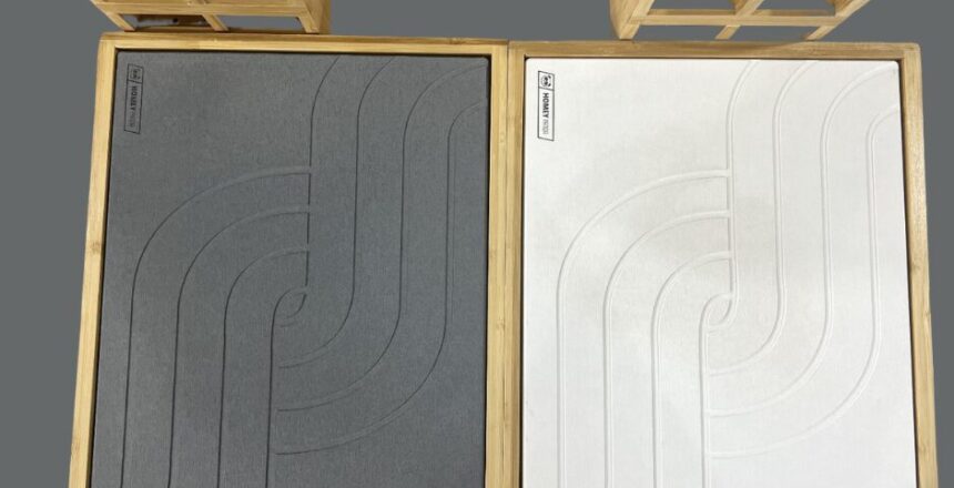 two bamboo drying stone mats with different colored textured surfaces, grey and white, placed side by side on a wooden countertop.